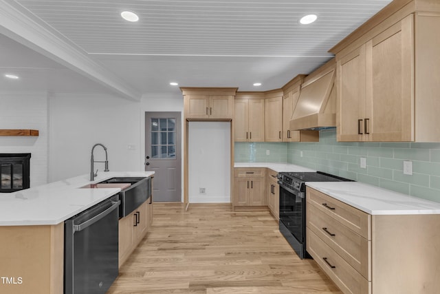 kitchen featuring light wood-type flooring, wall chimney exhaust hood, stainless steel dishwasher, black range with electric cooktop, and a sink