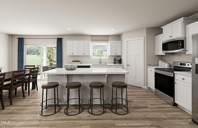 kitchen featuring a center island, a kitchen bar, appliances with stainless steel finishes, and light wood-style flooring