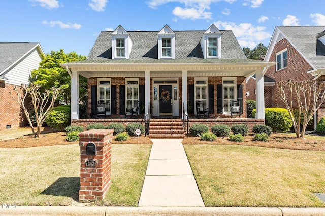 view of front of home with brick siding, roof with shingles, a porch, and a front yard