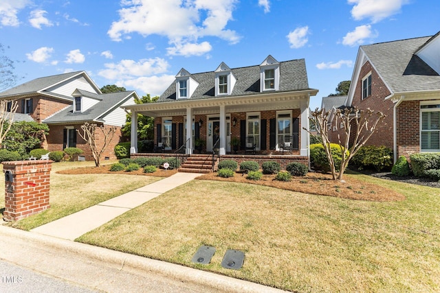 view of front of home featuring covered porch, brick siding, a front yard, and a shingled roof