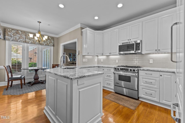 kitchen with white cabinetry, crown molding, an inviting chandelier, and stainless steel appliances