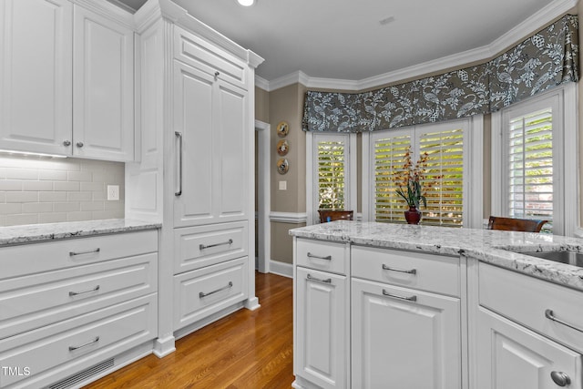 kitchen with crown molding, light wood-style flooring, backsplash, and white cabinets