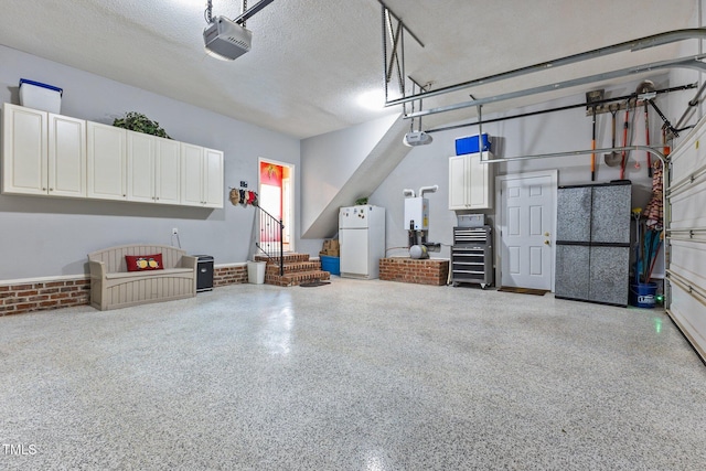 garage featuring water heater, a garage door opener, and freestanding refrigerator