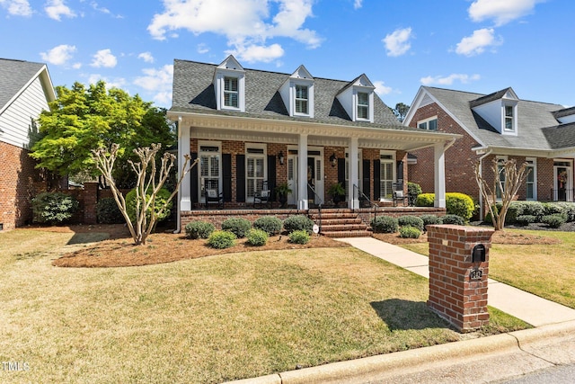 view of front facade featuring covered porch, a front lawn, and brick siding