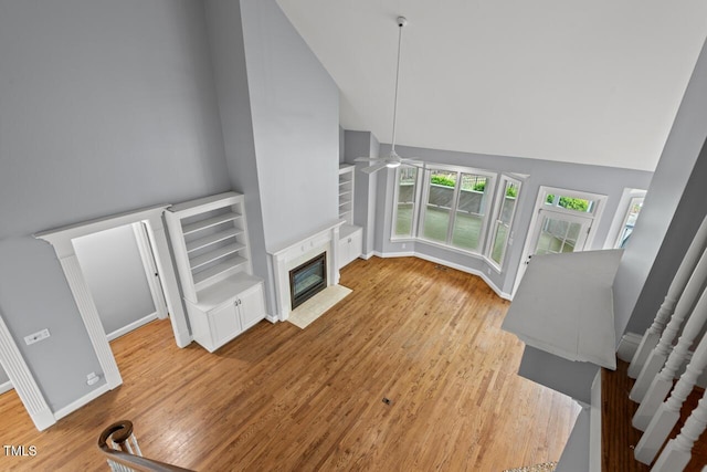 5900 Orchid Valley Rd, Raleigh, NC 27613 - unfurnished living room featuring ceiling fan, high vaulted ceiling, a fireplace with flush hearth, wood finished floors, and baseboards