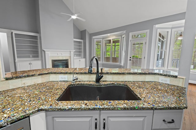 5900 Orchid Valley Rd, Raleigh, NC 27613 - kitchen with a sink, ceiling fan, wood finished floors, dark stone countertops, and a glass covered fireplace