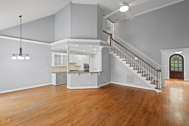 5900 Orchid Valley Rd, Raleigh, NC 27613 - unfurnished living room with high vaulted ceiling, stairs, light wood-type flooring, a ceiling fan, and a chandelier