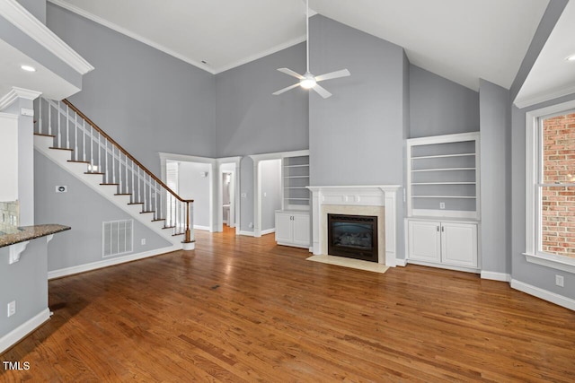 5900 Orchid Valley Rd, Raleigh, NC 27613 - unfurnished living room featuring a ceiling fan, stairway, wood finished floors, built in shelves, and high vaulted ceiling