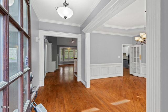 5900 Orchid Valley Rd, Raleigh, NC 27613 - entryway featuring wood finished floors, ornamental molding, wainscoting, a chandelier, and decorative columns