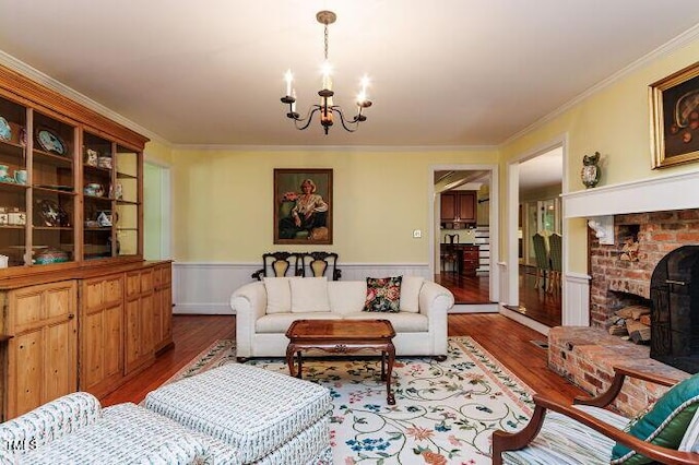 3005 Woodgreen Dr, Raleigh, NC 27607 - living room with wood finished floors, a chandelier, a wainscoted wall, crown molding, and a fireplace