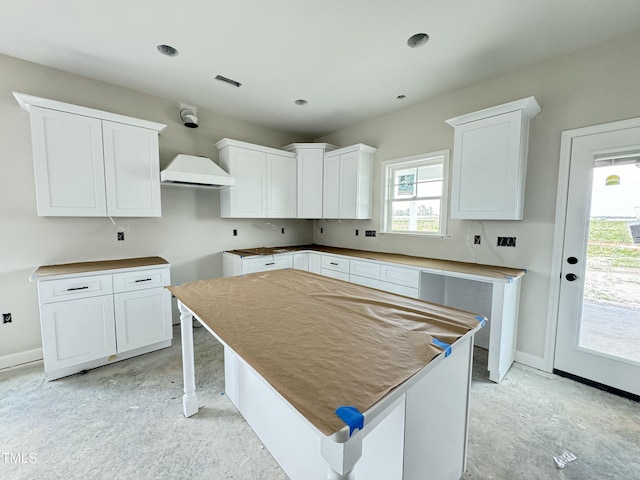 kitchen featuring a kitchen island, white cabinetry, and baseboards