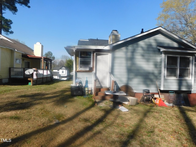 rear view of house with a wooden deck, a chimney, and a lawn