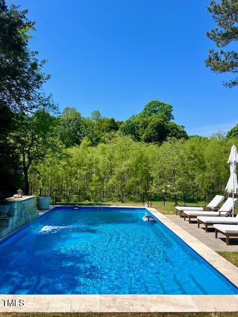 view of pool with fence, a fenced in pool, and a wooded view