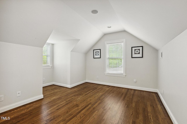 additional living space with wood finished floors, visible vents, baseboards, and lofted ceiling