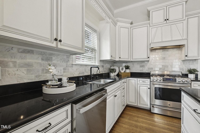 kitchen featuring a sink, ornamental molding, dark countertops, white cabinetry, and stainless steel appliances