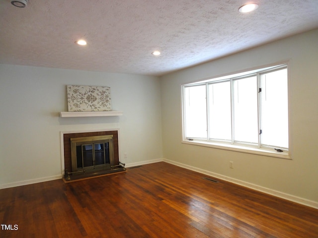 unfurnished living room with dark wood finished floors, baseboards, visible vents, and a tiled fireplace