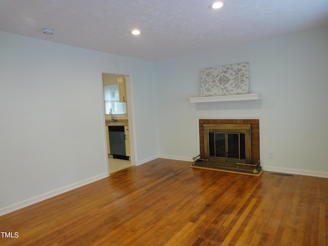 unfurnished living room featuring recessed lighting, baseboards, visible vents, a fireplace, and wood finished floors