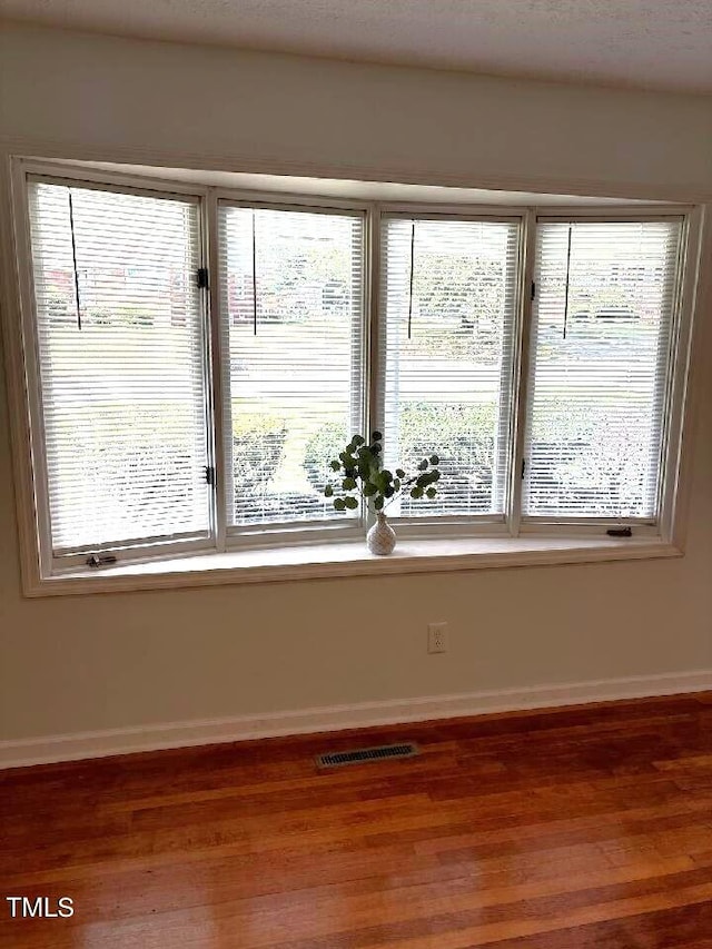 empty room featuring baseboards, visible vents, and wood finished floors