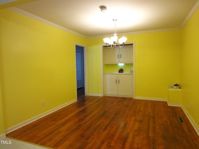 empty room with dark wood finished floors, visible vents, ornamental molding, and a chandelier