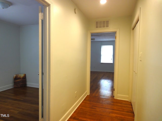 hallway with baseboards, visible vents, and dark wood-type flooring