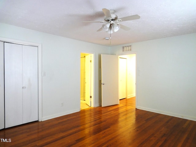 unfurnished bedroom featuring a closet, baseboards, visible vents, and wood finished floors