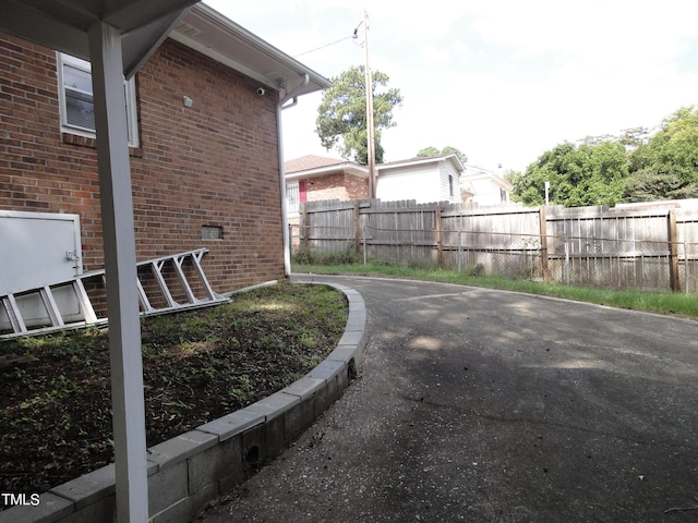 view of property exterior featuring brick siding and fence
