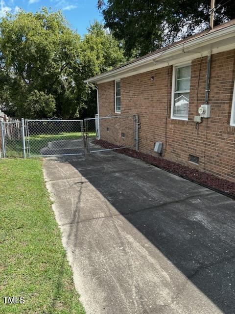 view of property exterior featuring a gate, fence, crawl space, brick siding, and a yard