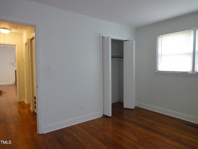 unfurnished bedroom featuring baseboards, dark wood-style flooring, a closet, and attic access