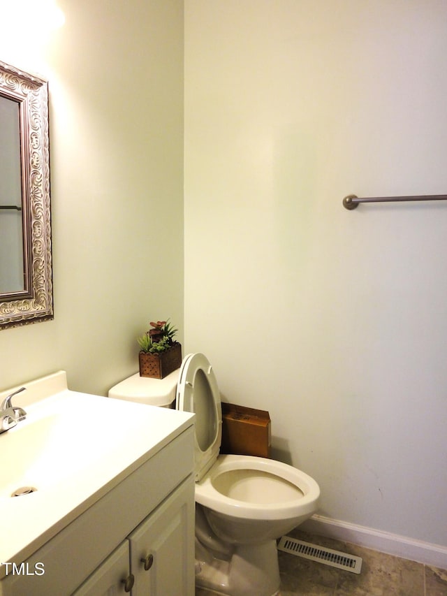 bathroom with toilet, vanity, baseboards, and visible vents