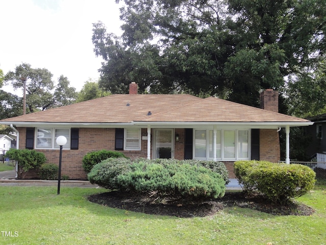 ranch-style house featuring brick siding, a front lawn, and a chimney