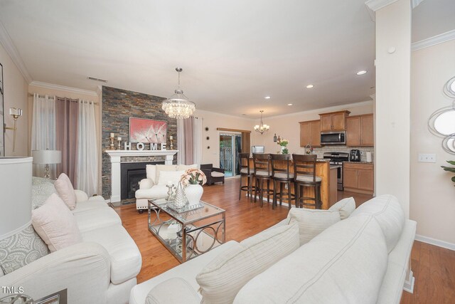 1030 Thoughtful Spot Ln, Durham, NC 27703 - living room with a chandelier, a fireplace, light wood finished floors, ornamental molding, and recessed lighting