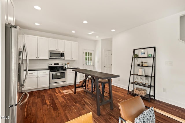 kitchen with appliances with stainless steel finishes, dark wood-style floors, white cabinets, recessed lighting, and baseboards