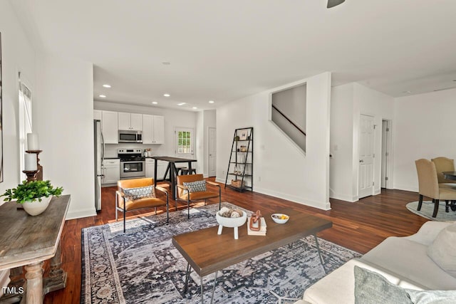 living area featuring dark wood-type flooring, baseboards, recessed lighting, and stairs