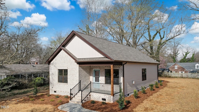 view of front of property with a porch, crawl space, roof with shingles, and brick siding
