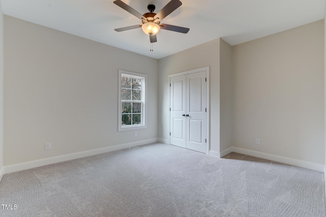 unfurnished bedroom featuring baseboards, a closet, ceiling fan, and carpet