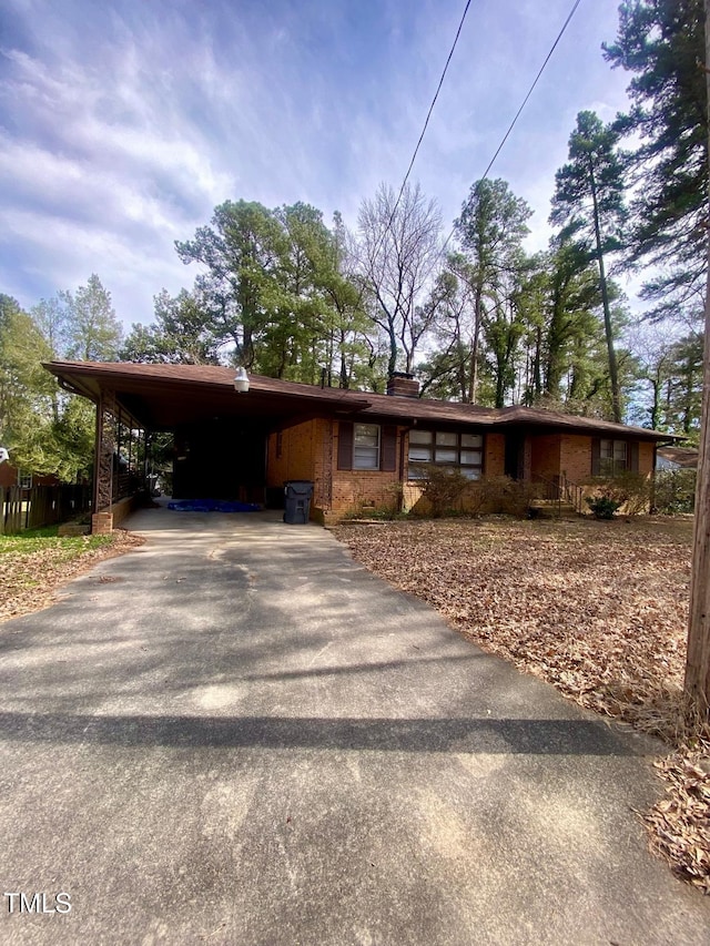 view of front of house featuring a chimney, a carport, and aphalt driveway