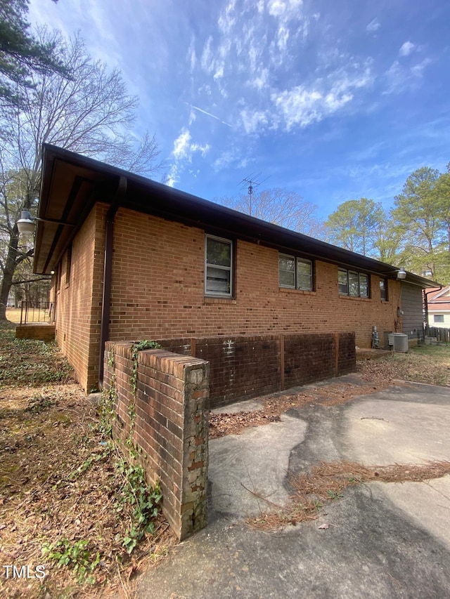 view of side of home featuring brick siding and cooling unit