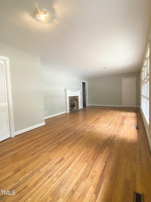 1115 Park Ave, Henderson, NC 27536 - unfurnished living room featuring light wood-style floors, baseboards, and a brick fireplace