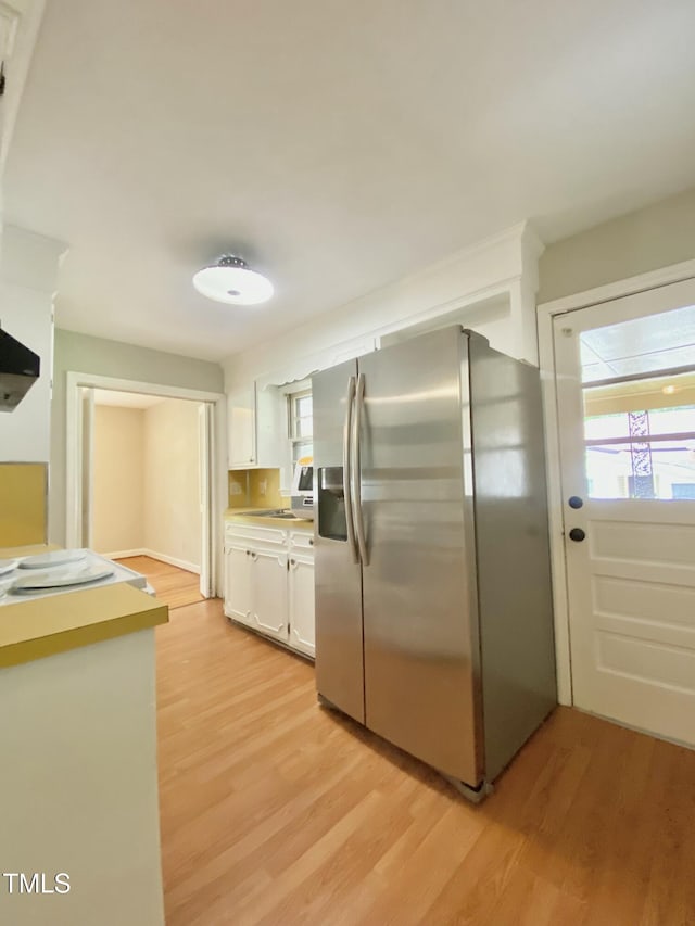 1115 Park Ave, Henderson, NC 27536 - kitchen featuring stainless steel fridge, white cabinetry, light wood-type flooring, and light countertops