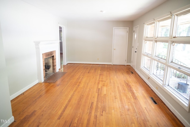 1115 Park Ave, Henderson, NC 27536 - unfurnished living room with light wood-type flooring and a brick fireplace