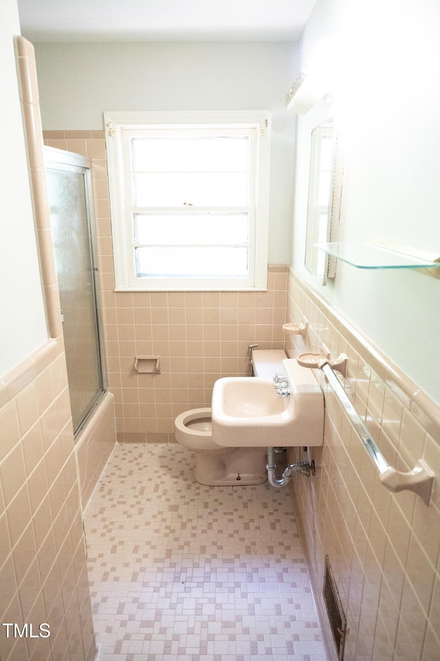 1115 Park Ave, Henderson, NC 27536 - bathroom with tile walls, a wainscoted wall, and shower / bath combination with glass door