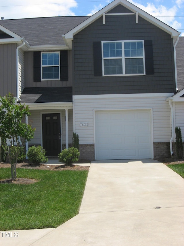 view of front facade featuring an attached garage, driveway, board and batten siding, a front yard, and roof with shingles