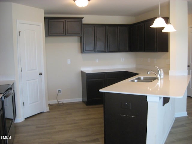 kitchen featuring a sink, a peninsula, wood finished floors, and a breakfast bar area