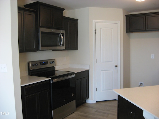 kitchen featuring stainless steel appliances, light wood finished floors, and light countertops