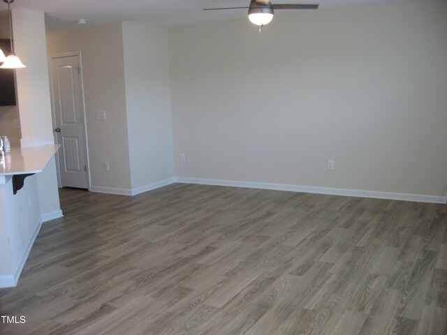 unfurnished living room featuring wood finished floors, ceiling fan, and baseboards