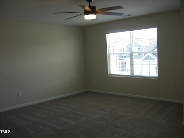 spare room featuring ceiling fan, dark carpet, and baseboards