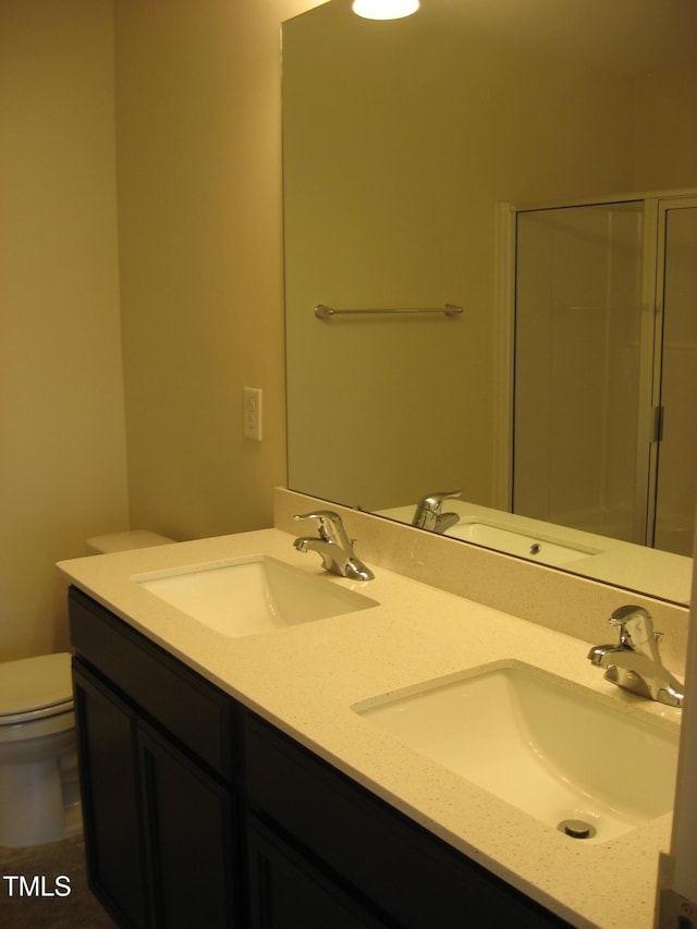 bathroom with toilet, double vanity, and a shower with shower door