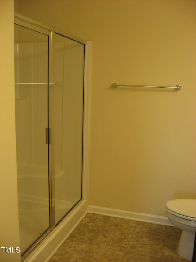 bathroom featuring a shower with shower door, baseboards, and toilet