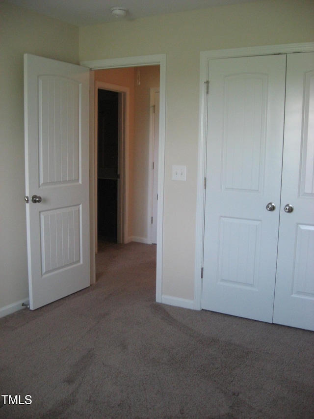unfurnished bedroom with carpet flooring, a closet, and baseboards