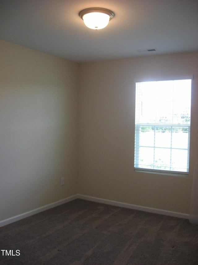 spare room featuring baseboards and dark colored carpet